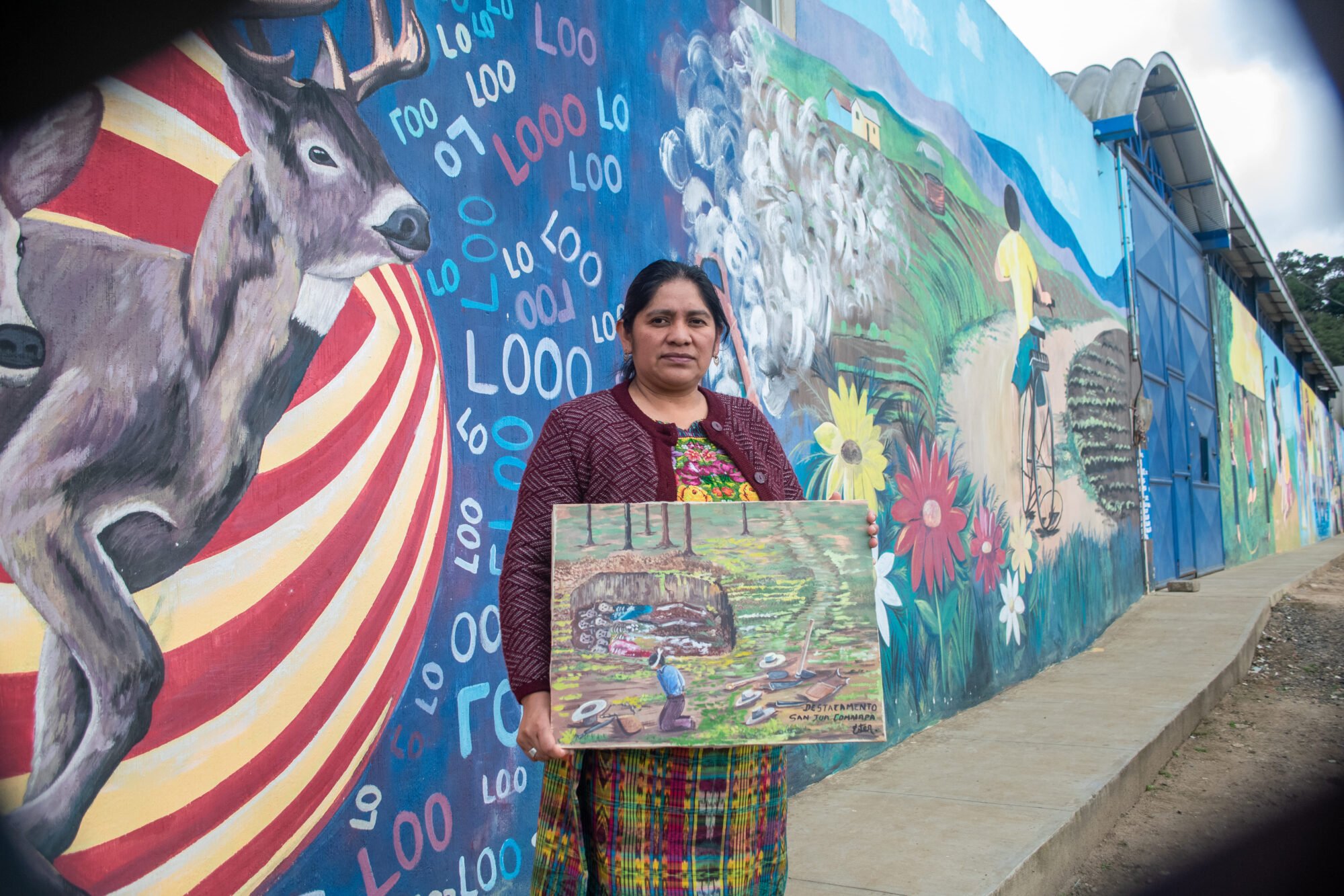  Miza sostiene una de sus pinturas que hace alusión al papel agresivo que jugó el destacamento militar en San Juan Comalapa, durante el conflicto armado. 