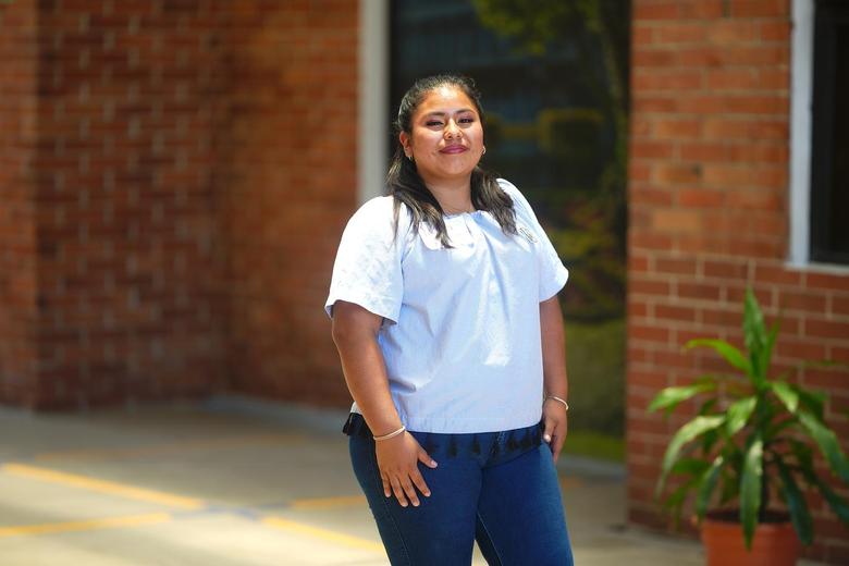 Mujer de pie, sonriendo, con las manos sobre los laterales de sus piernas.